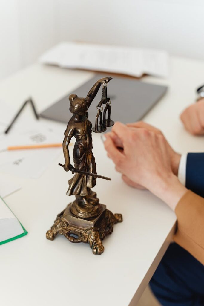 Crafting Captivating Headlines: Your awesome post title goes here Bronze Lady Justice statue on a white office desk with hands in the background. Symbol of law and fairness.