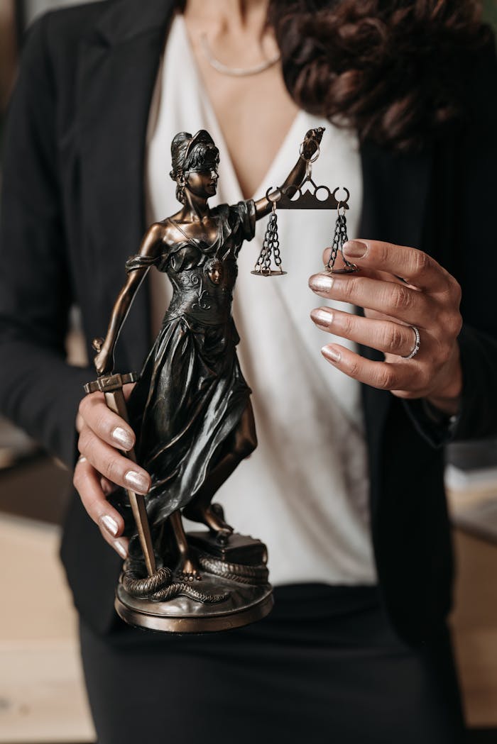 Close-up of Lady Justice statuette held by a lawyer, symbolizing law and justice.